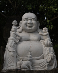 Laughing Buddha Statue with Children in Garden Setting

