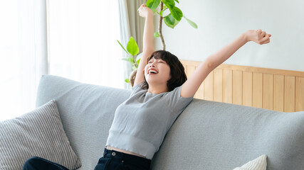 ソファで腕を伸ばしてリラックスする女性