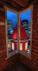 Obraz premium Cityscape View Through Red Roofed Window At Dusk