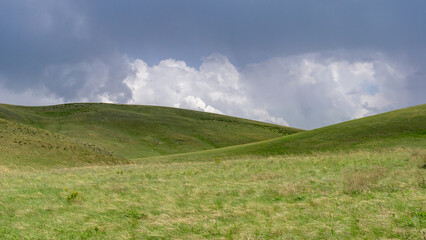 Long mountains. Lush green hills under a dramatic sky filled with clouds, showcasing the beauty of nature and the serene landscape in a peaceful rural environment