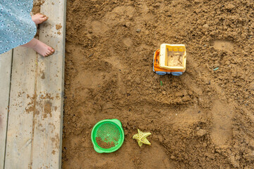 Toddler playing with sand toys in a sandbox. 