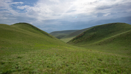 Long mountains. Lush green hills under a cloudy sky create a serene landscape, showcasing rolling terrain and vibrant grass, inviting exploration and connection with nature's beauty