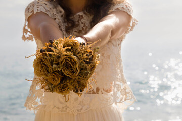 Dried wedding flower bouquet, ready for post-wedding photos on the beach. The bouquet is in the...