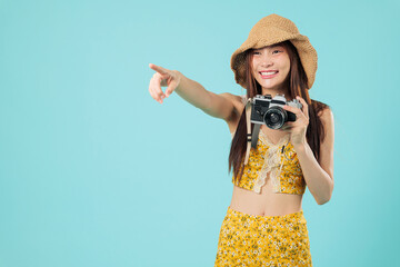 Happy tourist asian woman with a camera in a straw hat, pointing towards empty space and ready for...