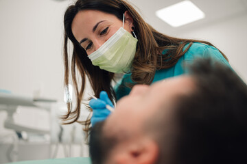 Dentist wearing surgical mask examining patient teeth in dental clinic