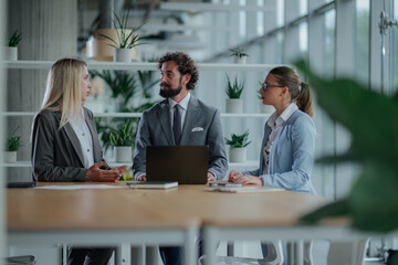 Businesspeople discussing work in modern office with laptop
