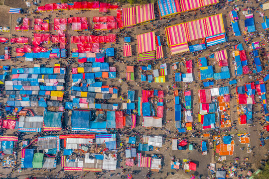 Bogura, Bangladesh - 09 February 2022: Aerial view of a vibrant and bustling market, a colorful tapestry of blue, red, and pink tents, teeming with countless people.