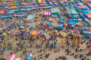 Bogura, Bangladesh - 09 February 2022: Aerial view of a bustling fair, a vibrant tapestry of colorful stalls and throngs of people under a clear sky.