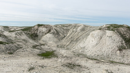 Pokrovsky Cretaceous mountains. Expansive arid landscape features rolling hills and rocky terrain, showcasing unique geological formations under a clear sky with soft clouds