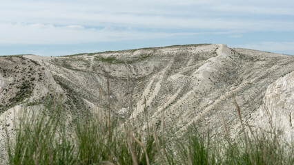 Obraz premium Pokrovsky Cretaceous mountains. Expansive view of rugged hills and grassy terrain under a cloudy sky, showcasing the natural beauty and textures of the landscape