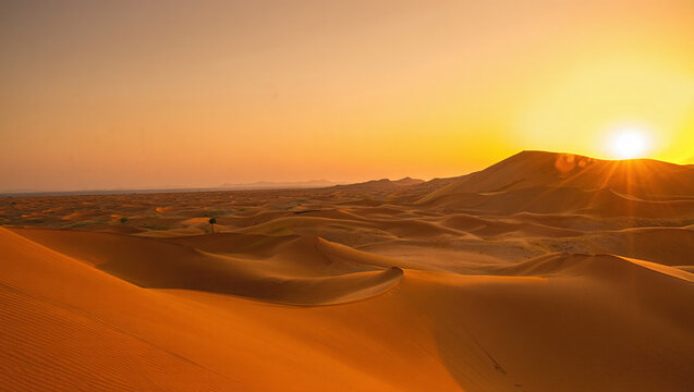 Desert Sunset with Sand Dunes and Sun Over Mountain