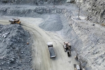 Trucks carry migmatite and crushed stone in quarry for the extra