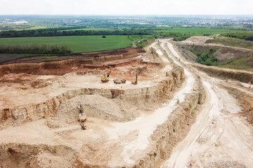 Excavators and dump trucks and other equipment in sand and grave