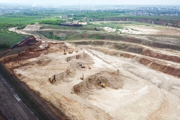 Excavators and dump trucks and other equipment in sand and grave