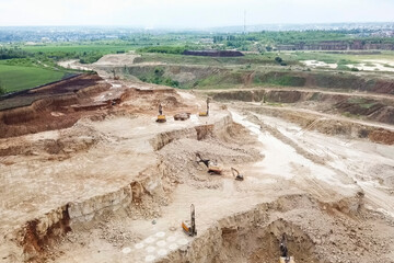Excavators and dump trucks and other equipment in sand and grave