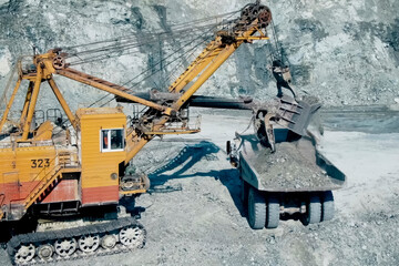 Picking and filling with an excavator bucket of crushed stone from pile of rock.