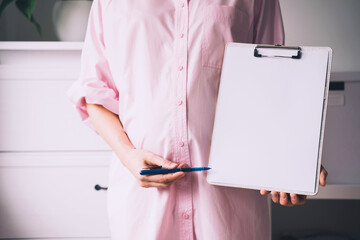 Pregnant woman with empty white paper as medical card, agreement blank. Template for text.