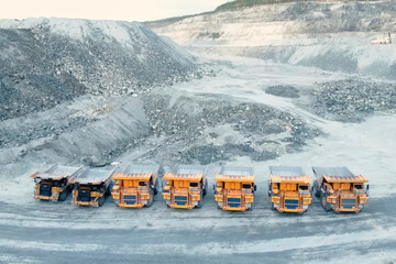 Mining dump trucks are parked in row. Equipment for an industrial quarry.