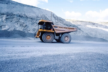 larger mining dump truck in the quarry against the background of rocks.