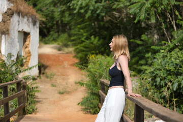 Young, pretty, blonde woman in black T-shirt and white pants, looking thoughtfully into infinity...