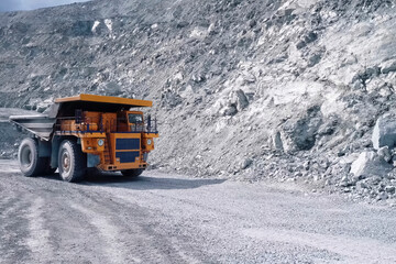 larger mining dump truck in the quarry against the background of rocks.