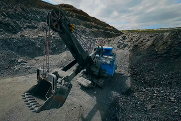 Mining excavator with bucket in industrial quarry. Crushed stone around.