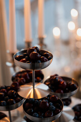 Beautifully arranged tiered berries display at a wedding reception, surrounded by glowing candles...