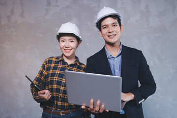 Construction manager and engineer dressed in orange work vests and hard helmets explore...