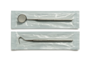 Dental mirror and hook in sealed sterile transparent packaging on grey background