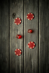 Red chips and dice with a combination of twelve during a game on a vintage wooden table in a pub....