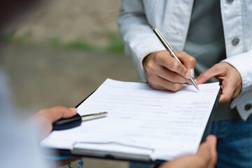 Insurance Documentation. A woman signing a form during an insurance consultation.