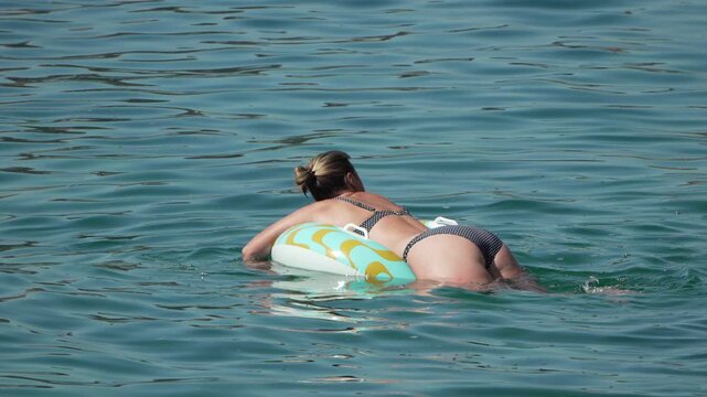 Woman swimming inflatable ring in blue ocean water during summer vacation