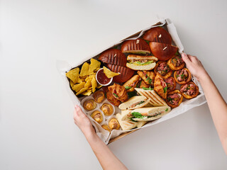 A colorful assortment of savory dishes is being held, showcasing different types of bread, meats, and accompaniments. This delightful spread is perfect for sharing at gatherings