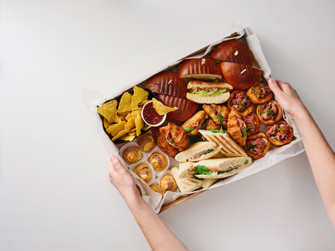 A colorful assortment of savory dishes is being held, showcasing different types of bread, meats, and accompaniments. This delightful spread is perfect for sharing at gatherings