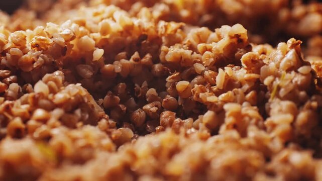 Cooked buckwheat macro, buckwheat groats close-up in a wooden spoon pouring background food video for cooking
