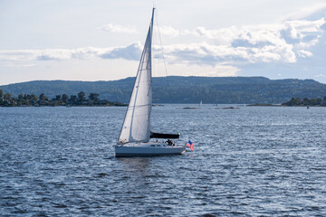 A sailboat flying the American flag is seen navigating the waters in Norway. The juxtaposition of...