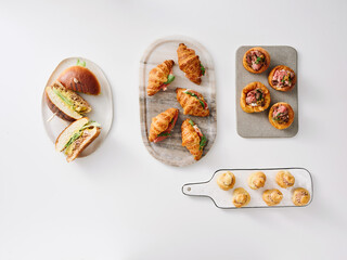 A variety of freshly baked pastries and sandwiches are beautifully arranged on platters. The scene captures an inviting brunch setting that highlights culinary artistry and presentation