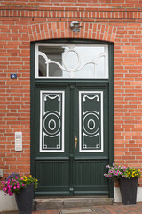 front door, a  detailed, frontal view of a traditional German doorway set within a rustic red brick...