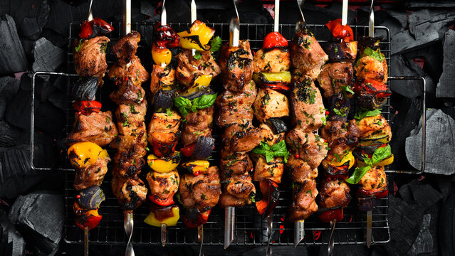 Set of Grilled kebab skewers on a background of hot coals. Barbecue, cooking meat on fire. On a black background.