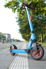 Blue electric scooter beside tactile paving on the city street