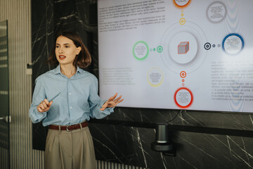 A professional woman leads a presentation with a digital display in a modern office setting, engaging a diverse business team in discussion and collaboration.