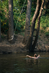 Teenage boy collecting rope swing in the river