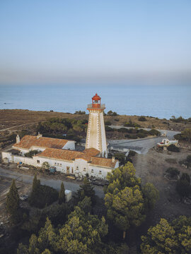 Aerial view of a striking white lighthouse with a red top standing sentinel against the tranquil blue sea, its light a promise amidst the rugged landscape, Leucate, Occitanie, France.