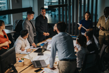 A diverse group of employees engaged in brainstorming and discussing ideas around a table....