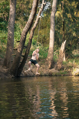 Teenage boy using rope swing at the river