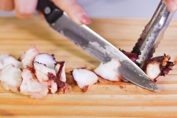 Using knife to cut octopus on cutting board