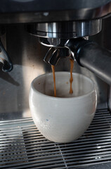 Close-up of an espresso machine brewing fresh coffee into a handmade ceramic cup.