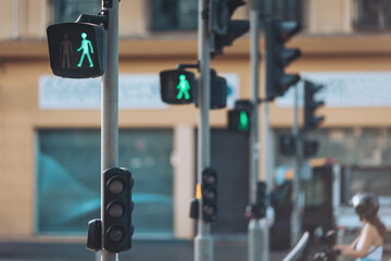 Green pedestrian signals light up the urban street as people navigate their way during a sunny midday