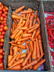 Fresh tomatoes, carrots, and red chili peppers displayed on a market. Perfect for organic food, healthy lifestyle, and traditional market photography.