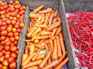 Fresh tomatoes, carrots, and red chili peppers displayed on a market. Perfect for organic food, healthy lifestyle, and traditional market photography.